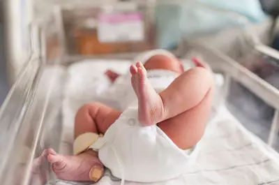 Baby lying in bassinette with Band-Aid on heel