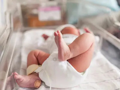 Baby lying in bassinette with Band-Aid on heel
